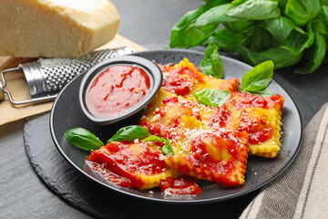 Delicious ravioli with tomato sauce, cheese, grater and basil on grey table, closeup