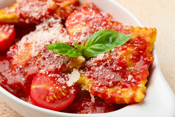 Delicious ravioli with tomato sauce, cheese and basil in baking dish on light table, closeup