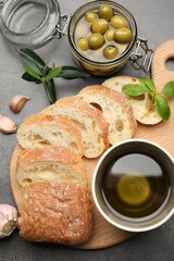 Slices of ciabatta, spices and olives on grey table, flat lay