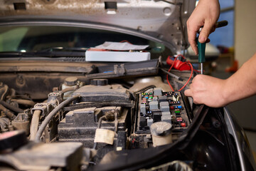 Professional technician tests battery and wiring connections precisely, Automotive specialist uses multimeter to assess engine circuitry and ensure proper functioning