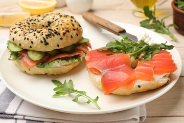 Delicious bagels with salmon served on wooden table, closeup