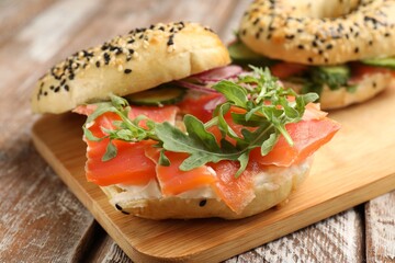 Delicious bagels with salmon on wooden table, closeup