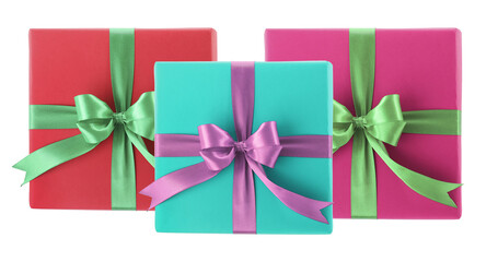 three brightly colored, contemporary square gift boxes wrapped in vibrant paper and tied with contrasting satin ribbons and neat bows isolated on black.