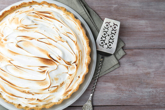 Delicious meringue pie and cake server on wooden table, flat lay. Space for text