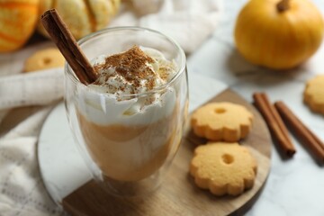 Tasty pumpkin latte with whipped cream in glass, cookies and ingredients on white marble table, closeup. Space for text