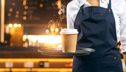 Professional barista presenting a fresh, steaming hot beverage in a disposable cup for takeaway service at a modern coffee shop