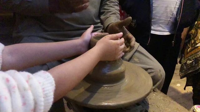A close-up and selective-focus image of a young child working with clay on a pottery wheel at Lok Virsa, Pakistan. Showing early learning, creativity, cultural art,