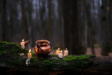 witch copper cauldron and burning candles on mossy trunk, abstract natural dark forest background. magic ritual, witchcraft. esoteric spiritual practice. fairytale, mystery atmosphere