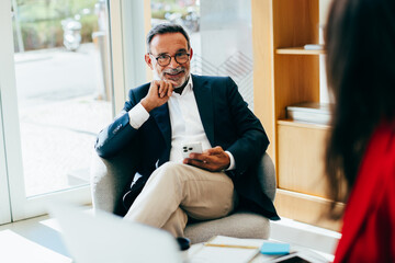 Senior professional man interacting with a colleague in a modern office setting