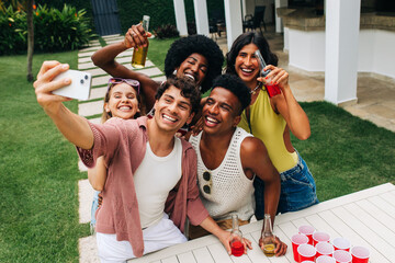Friends take a sunny outdoor selfie at a party