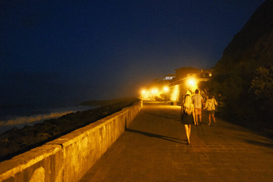 Jogging at night on lively urban coastal pathway with lights