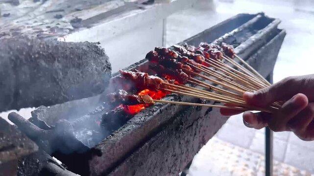 A close-up video capturing the process of grilling satay at a traditional street food stall