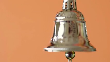 Silver bell hanging with a warm orange background for a celebration, greeting, or announcement