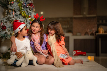 Three children enjoy Christmas Eve under a beautifully decorated tree, opening gifts with joy and curiosity. A cozy holiday atmosphere filled with love, tradition, and magic.