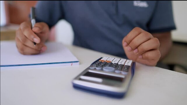 Person Calculating and Writing Notes, Person using a calculator and writing on paper