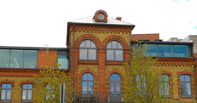 Renovated historic brick building with arched windows and modern glass extensions. A blend of classic and contemporary urban architecture. Real estate, and property marketing.
 - Powered by Adobe
