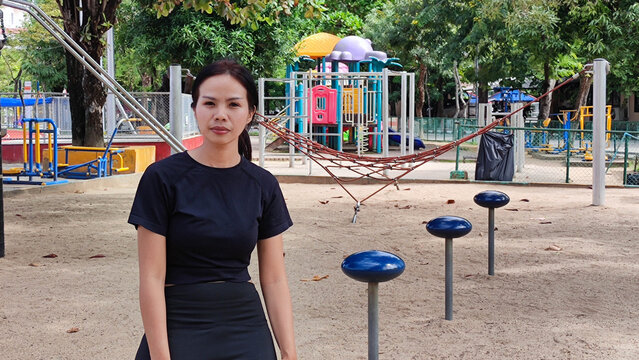 Solitary Contemplation: A woman stands serenely in a vibrant children's park, exuding a sense of introspection amidst the lively play area.