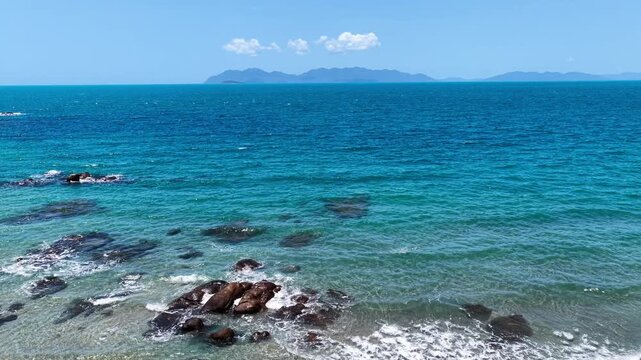 Beautiful aerial footage showcasing the turquoise waters and rocky shoreline of Rose Bay in Bowen. Clear shallows reveal reef textures as the camera glides along the coast, capturing the colours.