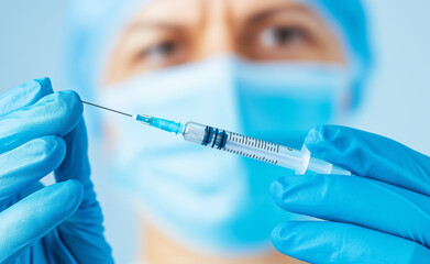 Close-up of a medical professional holding a syringe filled with liquid, prepared for injection.
