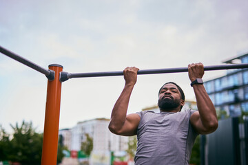 Naklejka premium Strong Man Doing Pull-Up On Outdoor Fitness Bar In Urban Park During Workout