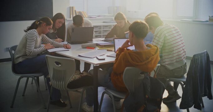 Young Pupils Deeply Concentrated Around Shared Table, Working on Group Project Using Mix of Laptops, Tablets, Notebooks. Concept Digital Learning, Teamwork in Modern Learning Environment. Dolly Shot.