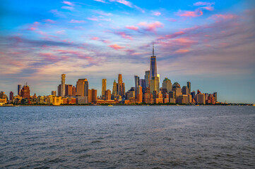 Panoramic view of New York City showing Lower Manhattan, the Financial District, and One World Trade Center at sunset, seen across the Hudson River from New Jersey.