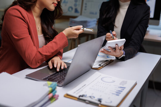 Businesswomen collaborating on financial data using laptop and calculator
