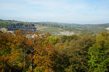 Vast Autumn Landscape With Colorful Trees, A Quarry, And Rolling Hills Under A Bright Blue Sky At Black Rocks, Cromford, Derbyshire.