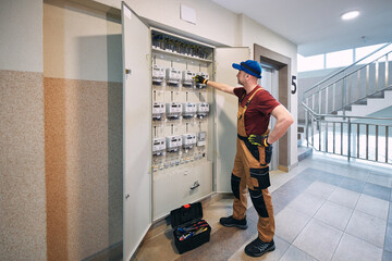 Electrician working on a modern electricity power meter station in a building.