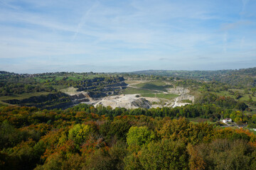 Panoramic View Of Black Rocks Quarry And The Vibrant Autumn Landscape With Hills And Distant Village Near Cromford, Derbyshire, Under A Blue Sky.