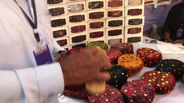 Man Brushing and Cleaning Traditional Embroidered Caps (Topi) for Sale in Local Market