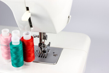 multi-colored sewing reels with threads stand against the background of a sewing machine. taken in close-up, with a place for text or an object