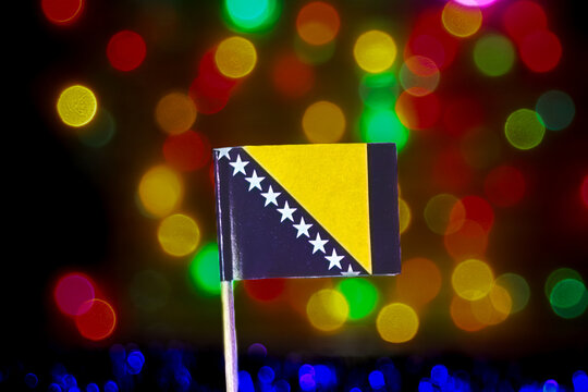 Bosnia and Herzegovina flag against a vibrant rainbow bokeh background, expressing national pride, New Year celebration themes, Balkan identity, tourism, and sports event energy. - Powered by Adobe