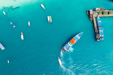 A high speed ferry arrives at a tropical island pier with tourists against the backdrop of...