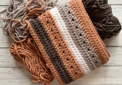 Knitted striped scarf made of warm yarn and thread. Needlework, hobbies. Backgrounds and textures. Winter, autumn. - Powered by Adobe