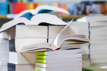 stack of books, close up. Open book on the table in library. Back to school concept. Open book on table with blur bookshelf background