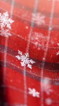 Vertical video: Opening close-up, swaying red plaid fabric surface, drifting white snowflake motifs