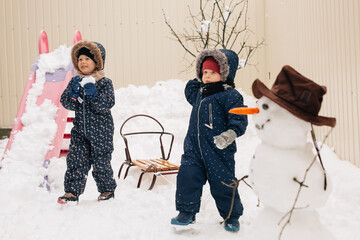 Children playing outdoors with snowman in winter yard