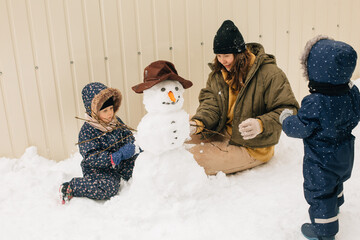 Family building snowman creating winter memories