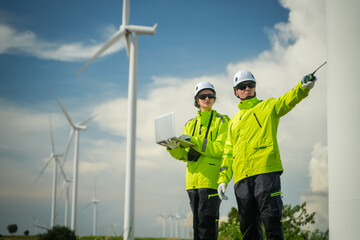 Wind energy engineers assessing turbine efficiency at wind farm outdoor setting professional collaboration