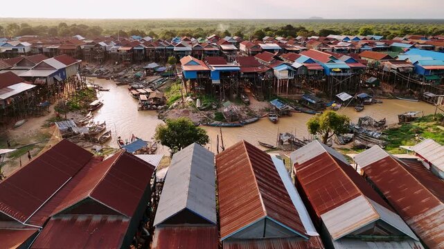 Aerial view of kampong phluk, a traditional floating village with stilt houses on the tonle sap lake in cambodia during a golden sunset.