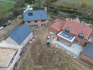 Drone inspection view of a large, near completed family home seen with a newly fitted glass lantern on the conservatory roof. Seen at a British housing development site.