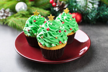 Christmas tree shaped cupcakes and festive decor on grey table, closeup