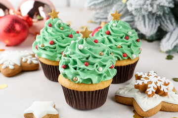 Christmas tree shaped cupcakes, festive decor and gingerbread cookies on white table, closeup