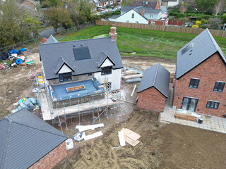 Drone view of a near completed detached family home in rural Britain. The back garden has had top soil laid, ready for grass seeding.