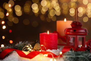 Burning candles and Christmas decor on table against dark background with blurred lights, closeup. Bokeh effect