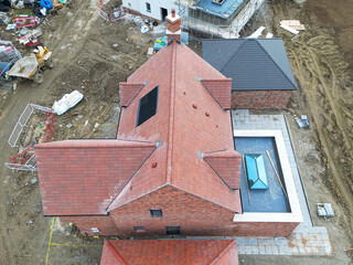 Drone inspection view of a large, near completed family home seen with a newly fitted glass lantern on the conservatory roof. Seen at a British housing development site.