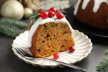 Slice of tasty Christmas cake with cranberries served on grey table, closeup