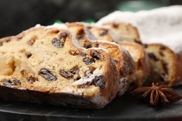 Pieces of traditional Christmas Stollen with icing sugar and anise star on table, closeup