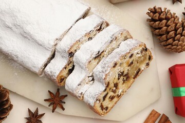 Cut traditional Stollen cake, gift and Christmas decor on white table, flat lay